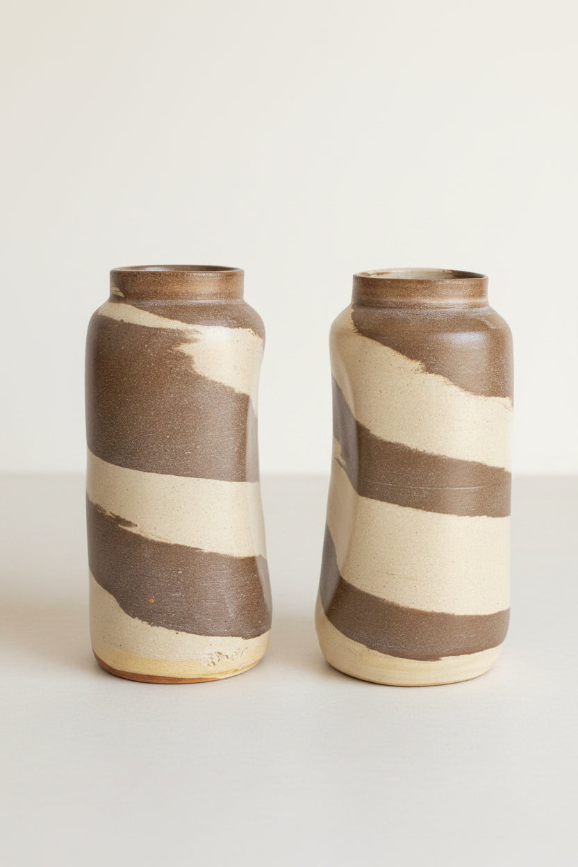 Two cylindrical slightly abstract ceramic vases with a marbled effect, featuring swirls of beige and brown.