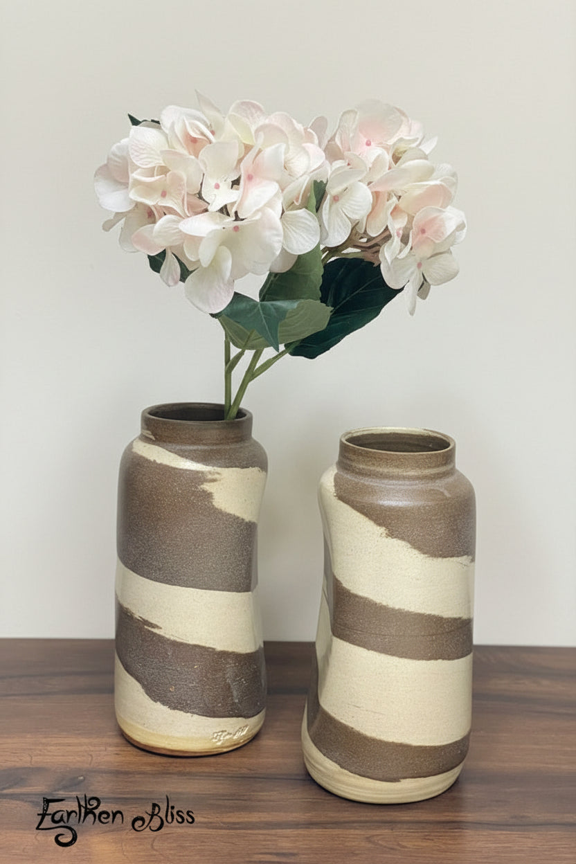 Two cylindrical slightly abstract ceramic vases with a marbled effect, featuring swirls of beige and brown.